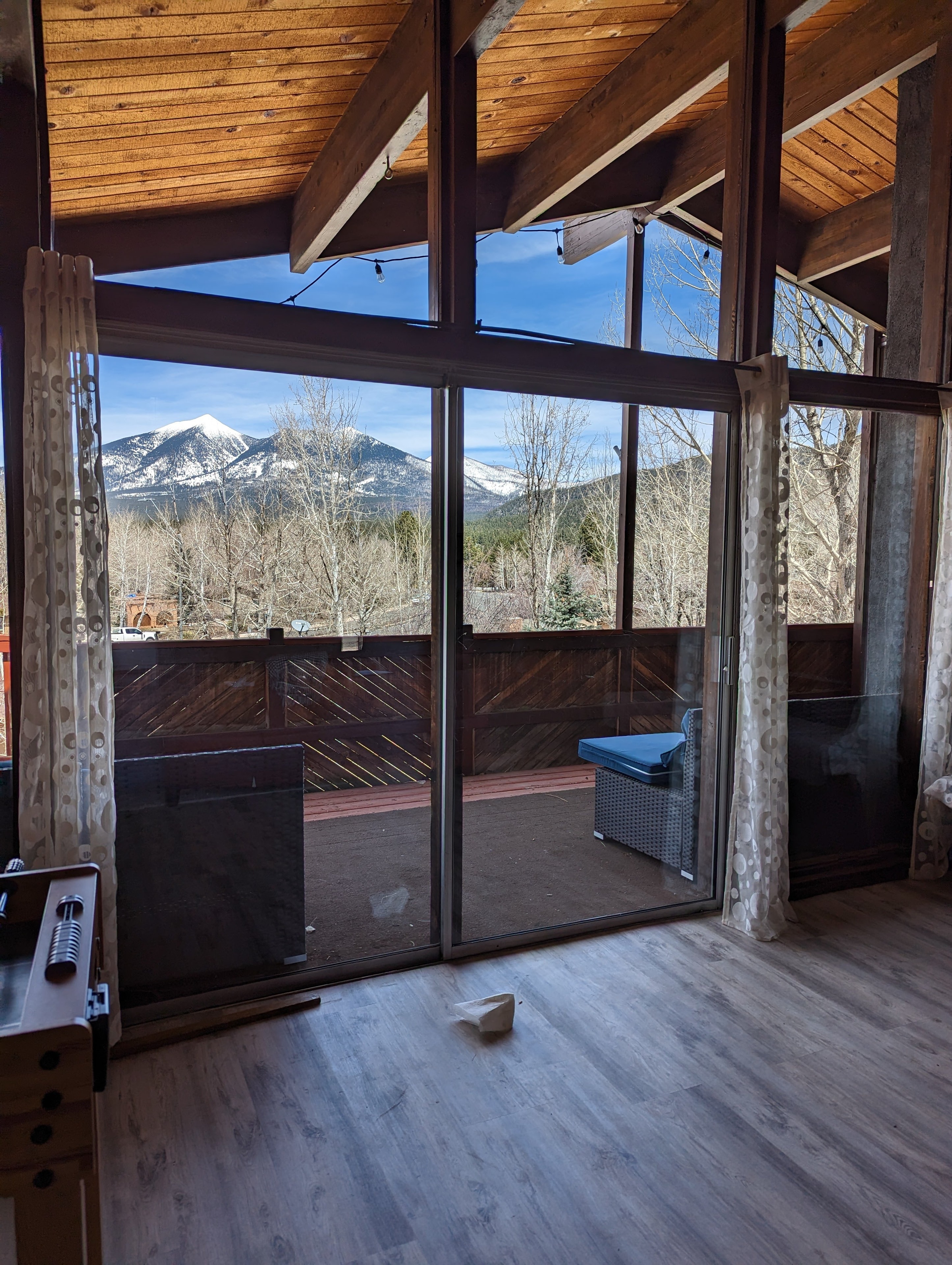 Clean sliding glass door and floor-to-ceiling windows at a Flagstaff log cabin home with snow-capped San Francisco Peaks visible through the glass