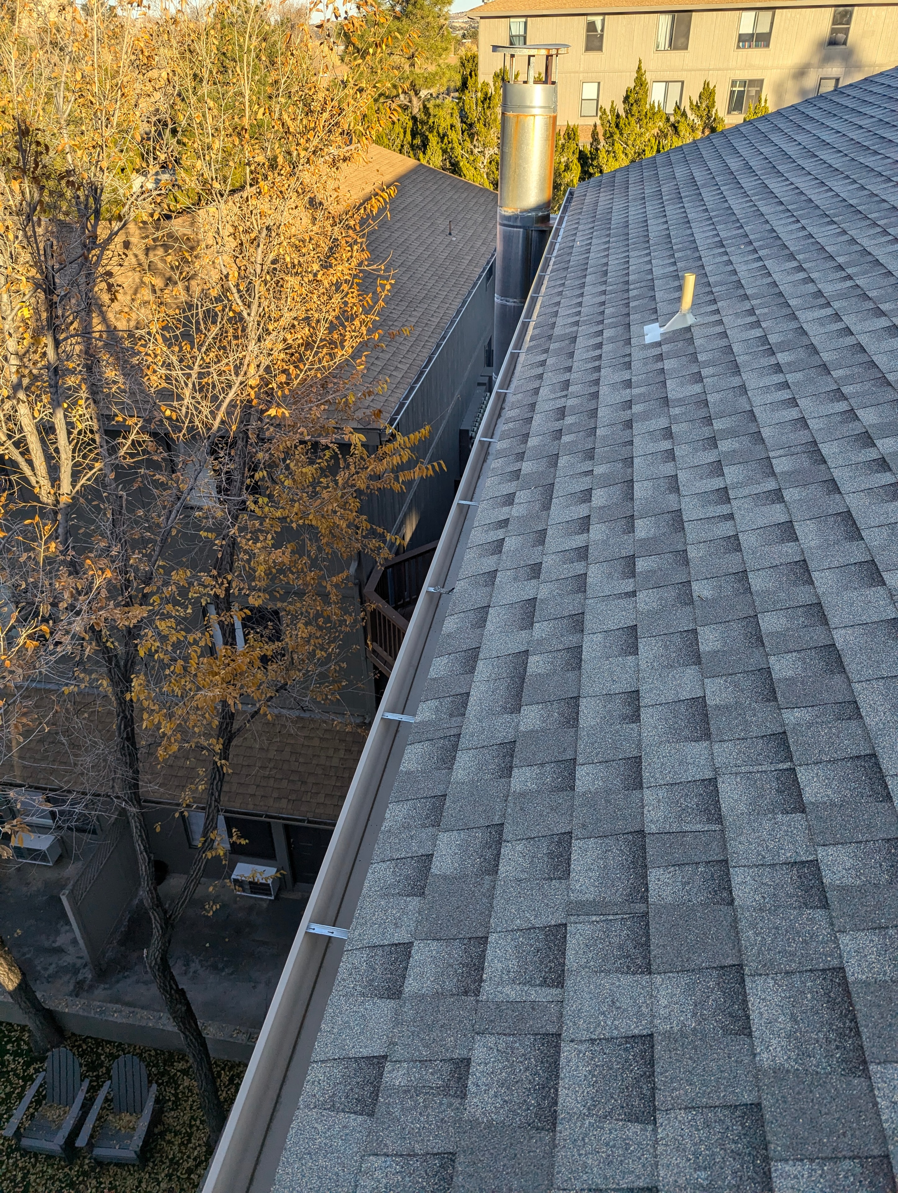 Aerial view of clean gutters on a shingle roof in Prescott, AZ with fall foliage and Prescott neighborhood visible