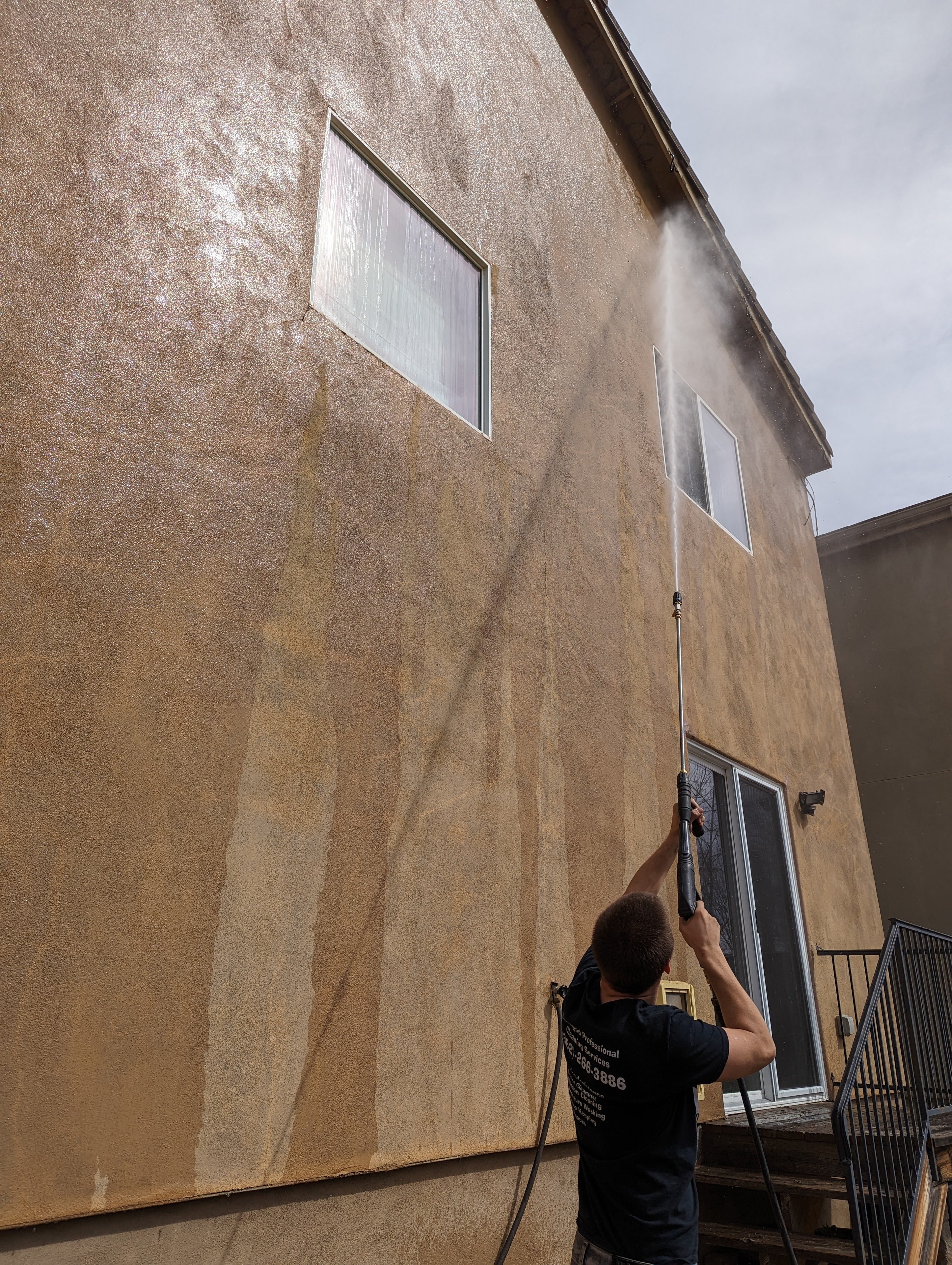 Demigod technician pressure washing the exterior of a two-story stucco home in Prescott, AZ