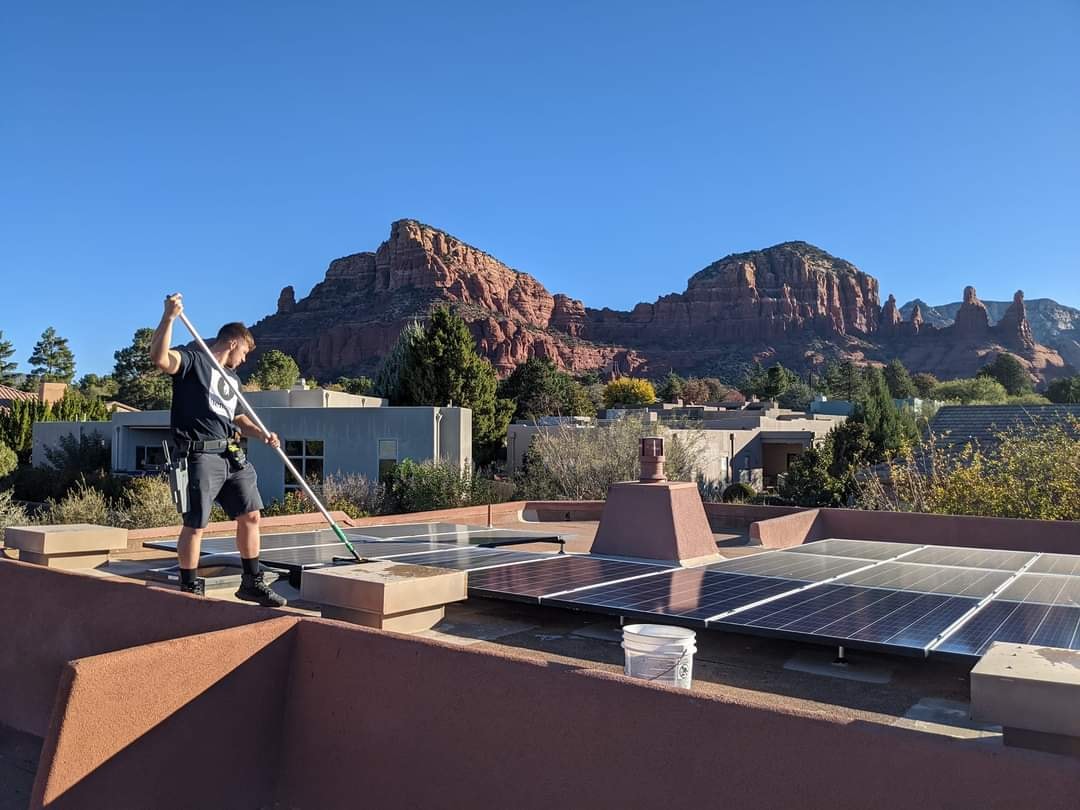 Solar panel cleaning on a flat rooftop in Sedona with red rock formations visible in background
