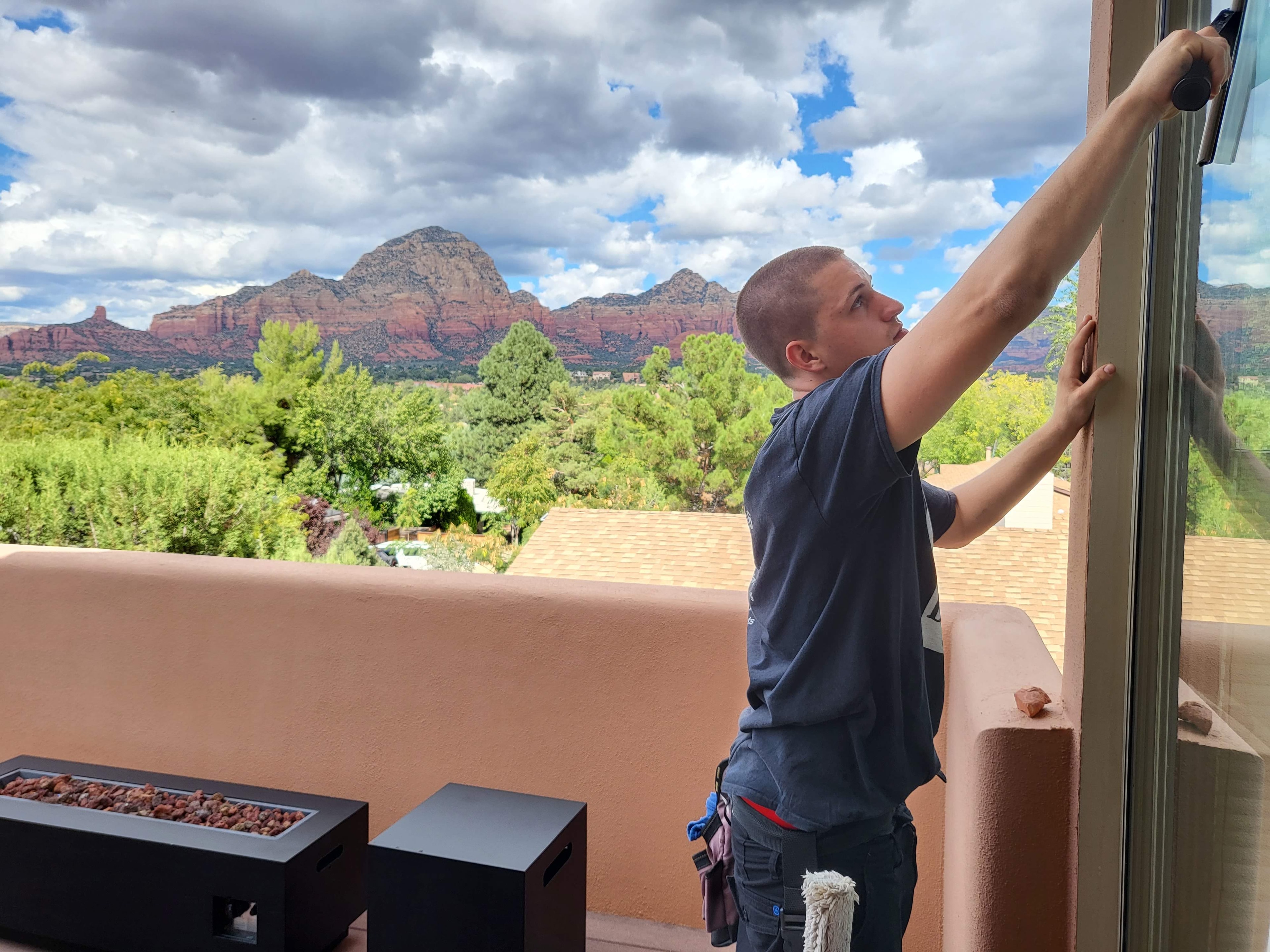 Demigod technician squeegee cleaning large windows at a Sedona luxury home overlooking red rock formations